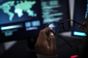 Hand holding eyeglasses with computer codes background