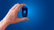 © AndSus - Modern shiny smart watch black color in hand on blue background. Smart watch displays time and the icon sync with cloud storage via the Internet. VECTOR