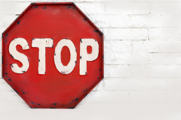 red stop symbol on a white brick wall, isolated object.