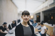 © Maskot - Portrait of female confident computer programmer at office with colleagues working in background
