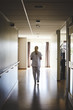 © Maskot - Full length rear view of female nurse walking in hospital corridor