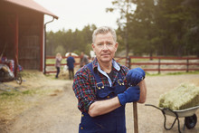 Portrait Of Confident Farmer Holding Pitchfork While Standing In Farm