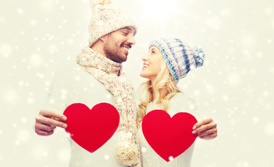 Canvas Print - smiling couple in winter clothes with red hearts