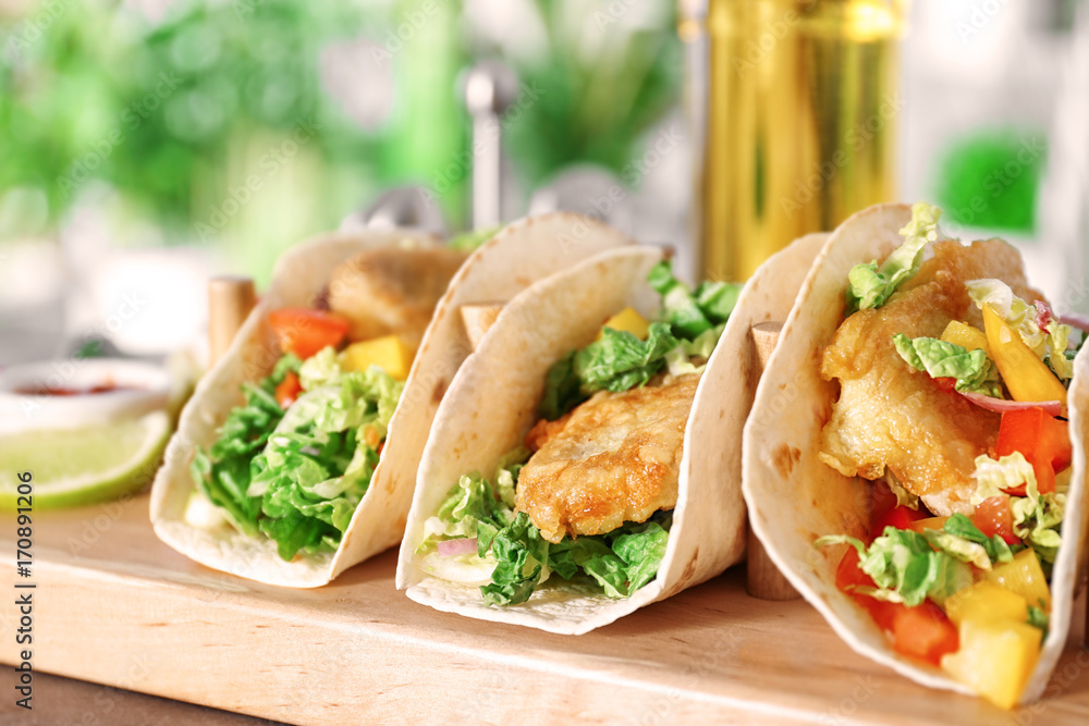 Wooden holder with yummy fish tacos on kitchen table
