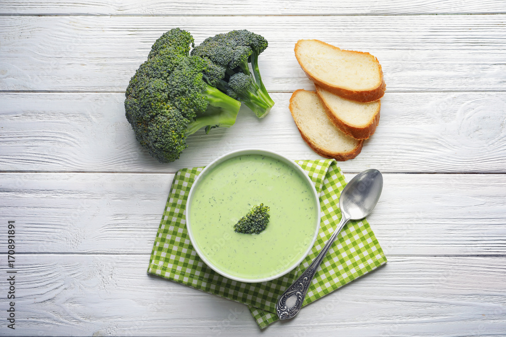 Composition with delicious broccoli soup on white wooden background