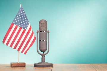 USA flag and big retro old microphone on wooden desk front mint green wall background. Vintage instagram style filtered photo