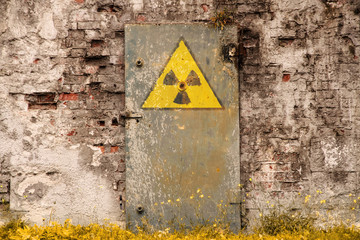 Wall Mural - Radioactive (ionizing radiation) danger symbol painted on the old massive rusted iron door of an abandoned structure with grunge walls and overall derelict atmosphere.