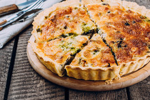 Quiche Lorraine with chicken and vegetables on rustic dark table background. Pie with mushrooms, chicken and broccoli on wooden kitchen board. Traditional French food.