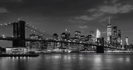 Fototapete - Time-lapse of Lower Manhattan Financial District skyscrapers, Brooklyn Bridge, and East River with passing clouds at twilight in Black & White. Manhattan, New York City