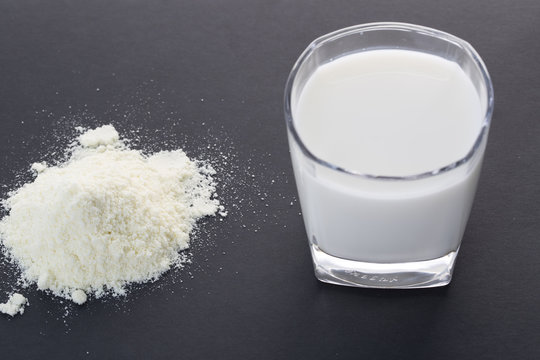 Fototapete - Powdered milk and glass cup of milk on the black background.