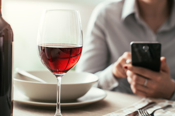 Wall Mural - Woman using a smartphone at the restaurant