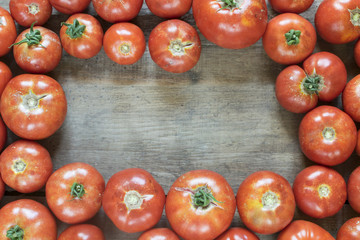 Group of fresh, red tomatoes forming frame on old wooden table with copy space. High angle view