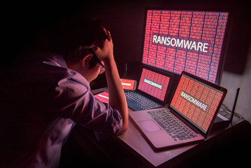 young asian male frustrated, confused and headache by ransomware attack on desktop screen, notebook 