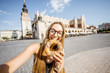 Young woman tourist eating prezel on the market square in Krakow in Poland