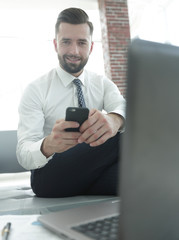 Canvas Print - businessman holding a smartphone and looking at the camera