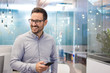 © Bojan - Portrait of cheerful businessman with mobile phone standing in modern office.