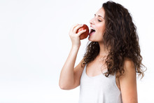 Beautiful Young Woman Eating Red Apple Over White Background.