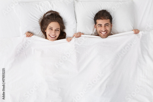 Top View Of Heads Of Happy Lovely Couple Lying In Bed And