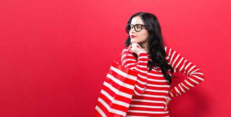 Young woman holding a shopping bag on a red background