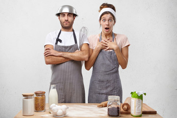 Wall Mural - Hard working male and female cookers work in restaurant, cook various dishes, look with surprisment as see many guests and visitors at cafe, realize that they should work hard and very quickly