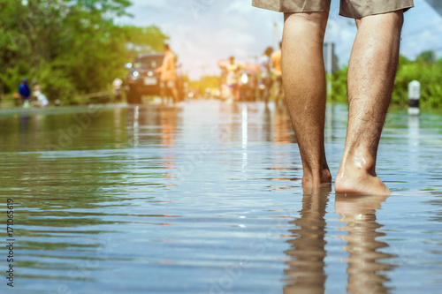 Plakat młody człowiek przechodzi przez powódź bosymi stopami.