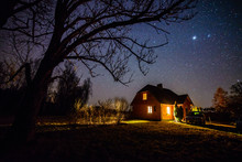 The Milky Way In Night Sky With Stars Over Wooden Country House At Night