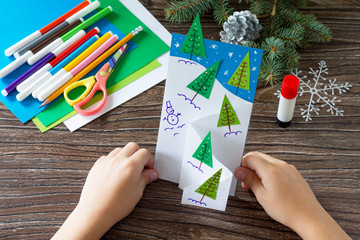 Wall Mural - The child makes a greeting card Christmas. Made with his own hands. Children's art project craft for kids. Craft for children.