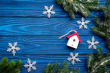 house toys and snowflakes to decorate christmas tree for new year celebration with fur tree branches on blue wooden background top veiw mockup