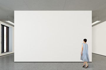 Woman looking at blank poster in modern gallery