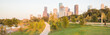 Panorama of downtown Houston, Texas, USA at sunset from Eleanor Tinsley Park. Grassy green park lawn, Buffalo Bayou river, curved pathway with people walking, biking, exercising and modern skylines.