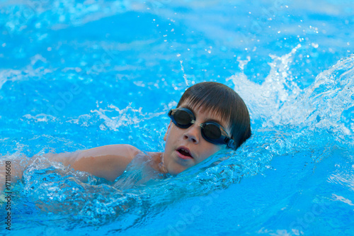 Plakat Chłopiec pływacki styl wolny w basenie / nastolatka chłopiec w czarny googles pływający styl wolny w pływackim basenie
