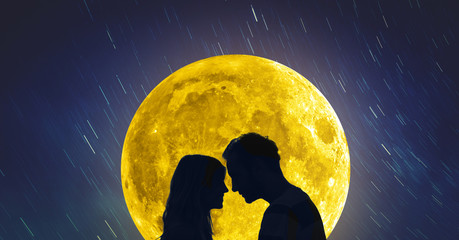 silhouettes of a young couple under the starry sky with full moon.