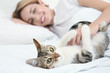 © Africa Studio - Young beautiful woman with cat lying on bed at home