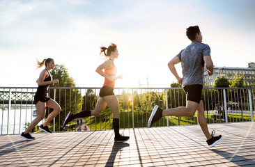 Canvas Print - Young athtletes in the city running at the river.