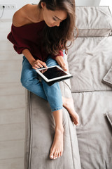 Wall Mural - Top view of a young woman in sweater using pc tablet