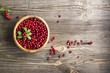 Red lingonberry in wooden bowl on rustic surface, top view