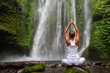 Poster - Woman meditating doing yoga between waterfalls