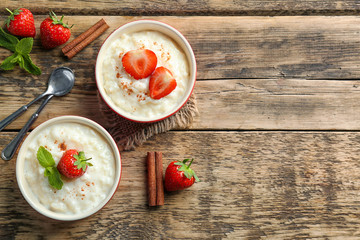 Wall Mural - Creamy rice pudding with strawberry on wooden table