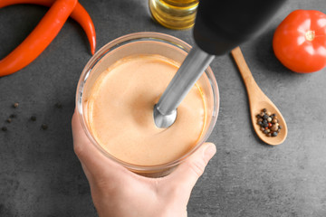 Canvas Print - Woman preparing tasty creamy tomato sauce for fish taco on kitchen table