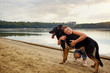 A girl hugs her dog on the beach in a park. A German shepherd with a young woman.