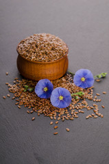 Wall Mural - Flax seeds in the wooden bowl, beauty flower and oil in caps on a grey background. Phytotherapy.