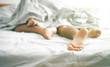 Close up of male and female feet on a bed - Loving couple having sex under under white blanket in the bedroom