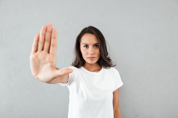 Serious young asian woman showing stop gesture with her palm