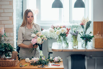 Wall Mural - Cute concentrated young female florist in glasses working in flower shop