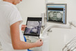 A female dentist holds an X-ray photo of a human skull from a profile on a computer background with a picture of the jaws in the dental office