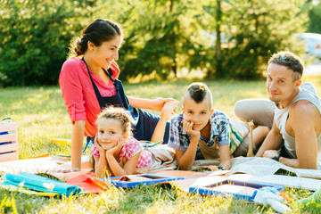 Wall Mural - Happy mother, father and two kids are painting in the park. The concept of a happy family.