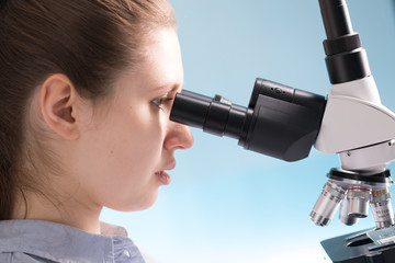 Poster - Doctor woman working  a microscope. Female scientist looking through a microscope in lab. Student girl looking in a microscope, science laboratory concept