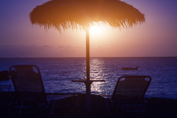 Beach umbrella and sun beds on the sea beach at sunset