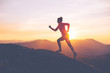 canvas print picture - Athletic girl finishes a run in the mountains at sunset. Sport tight clothes. Intentional motion blur.