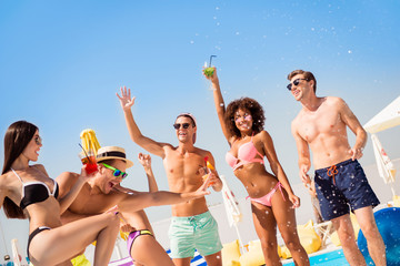 Canvas Print - Cropped shot of chilling, dancing international youth, enjoying on resort beach pool sunny disco, in diverse trendy fashionable bikinies, spectacles, caps, with drinks, celebrating holiday